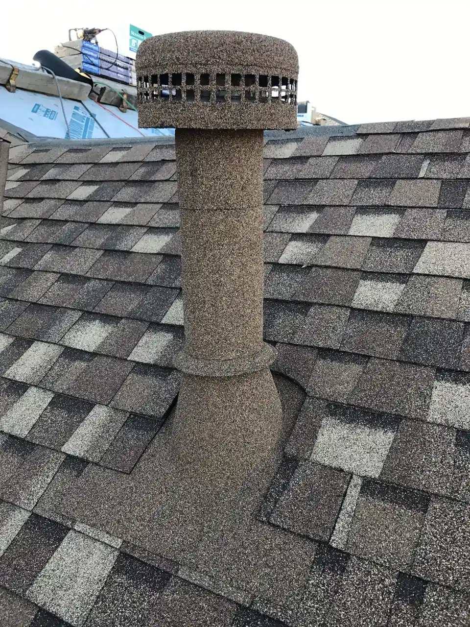 Water heater vent pipe and cap finished in stone coating to match a new gray shingle roof