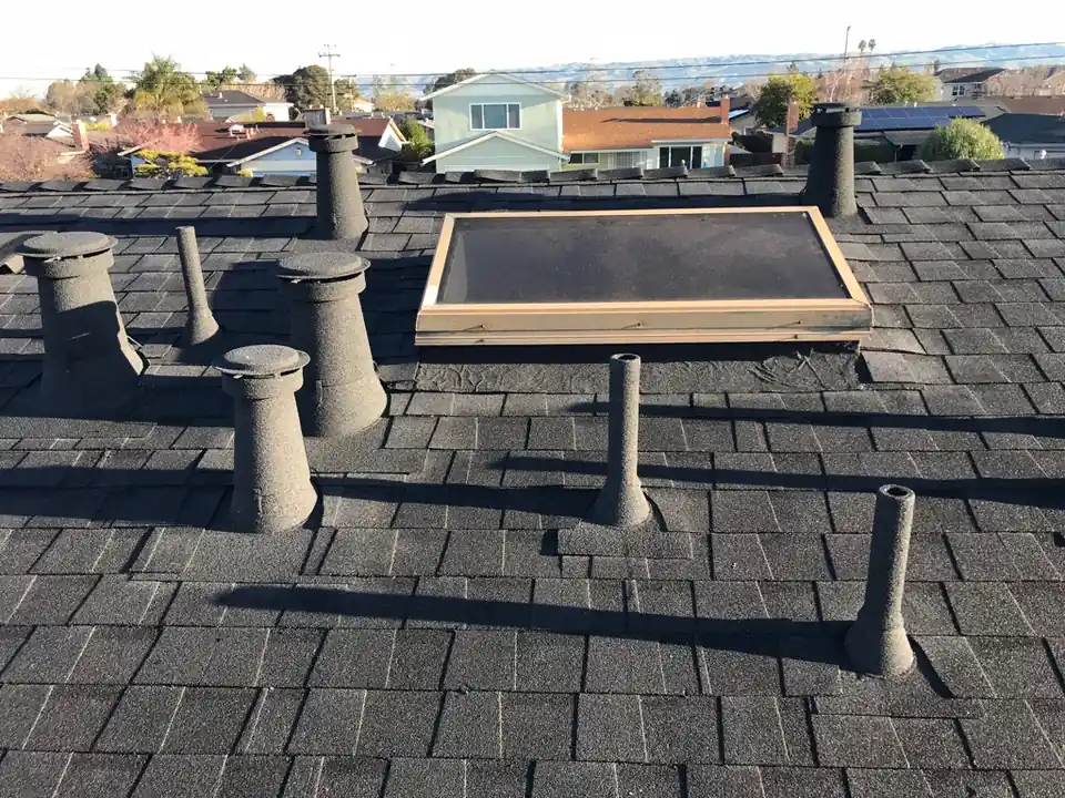 Finished composition shingle roof with every pipe, vent and skylight curb finished in stone coating that matches the shingles, rooftops and hills behind