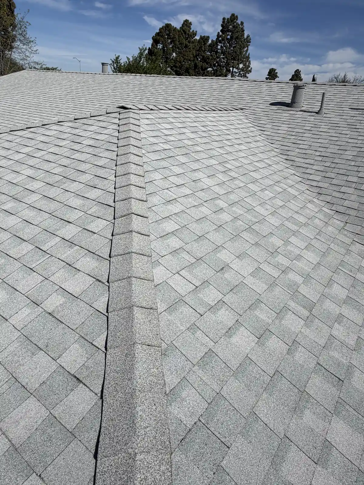 Looking up a light gray shingle roof along a stone-coated valley to a stone-coated vent at the ridge