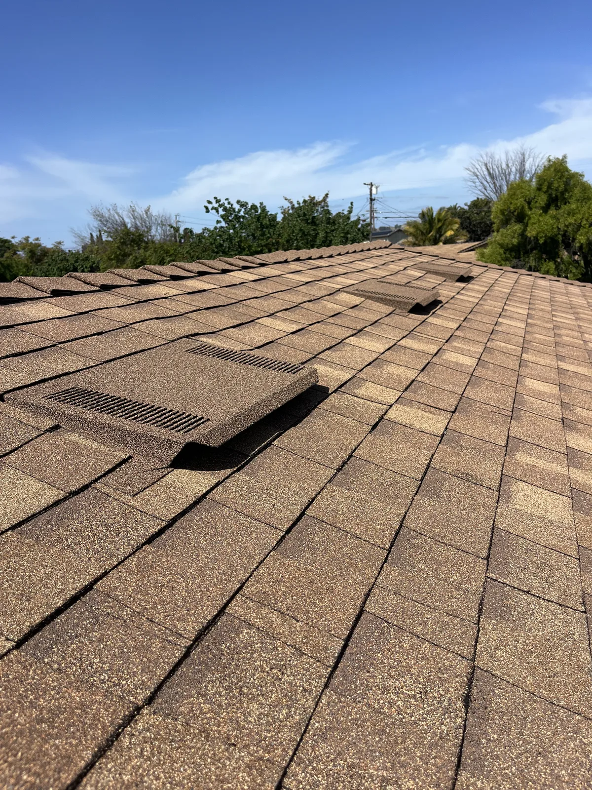 Close view of a low-profile attic vent seated flush in the shingles on a Sonrise roof, with a second vent further up the slope
